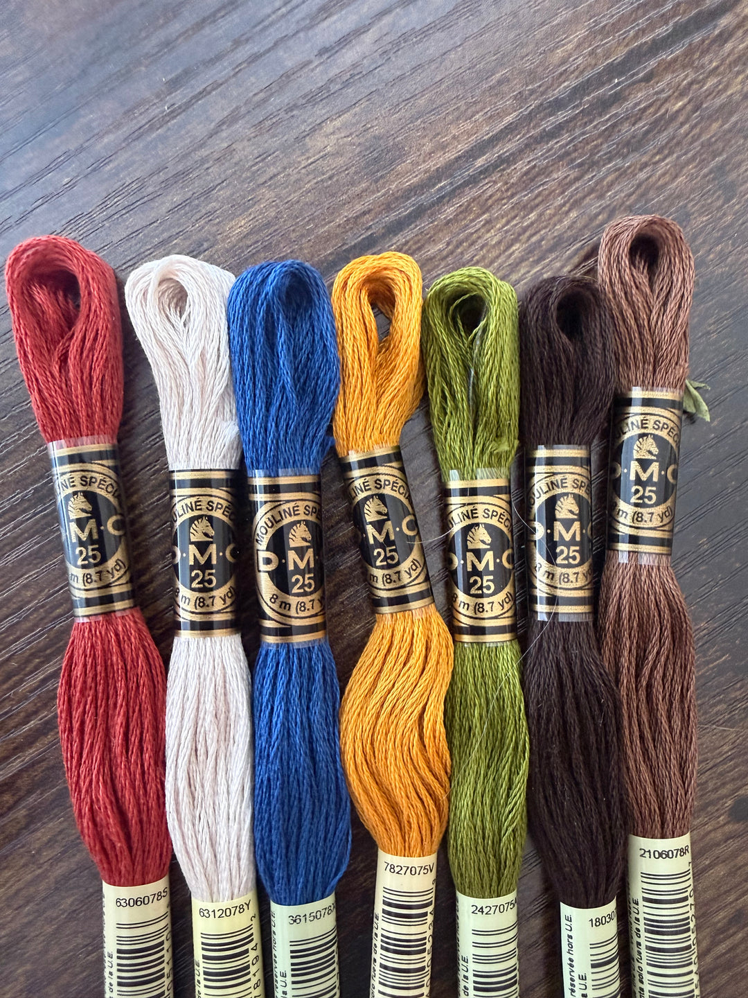 Set of embroidery threads in various colors on a wooden surface