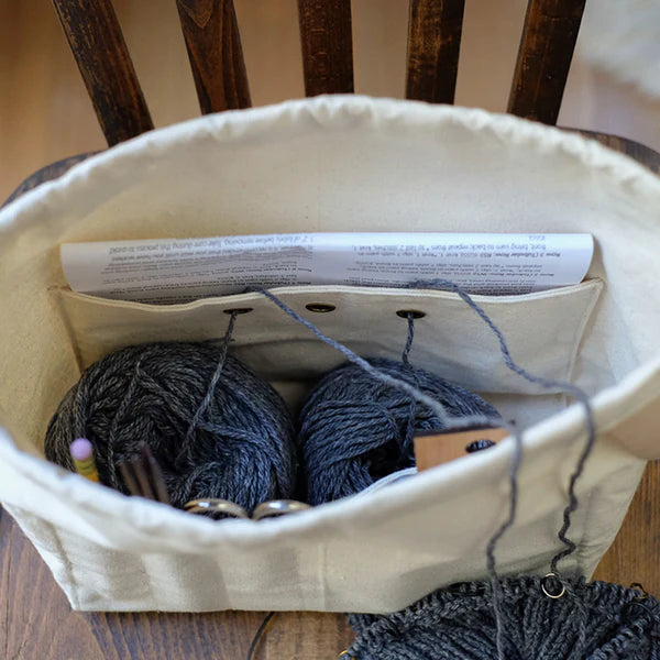 Canvas bag with yarn and knitting needles on a wooden chair