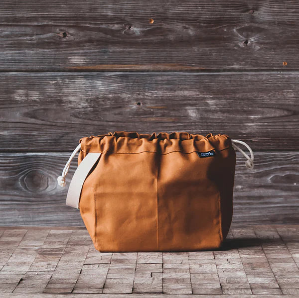 Brown leather bag with drawstring on a wooden floor and wall background