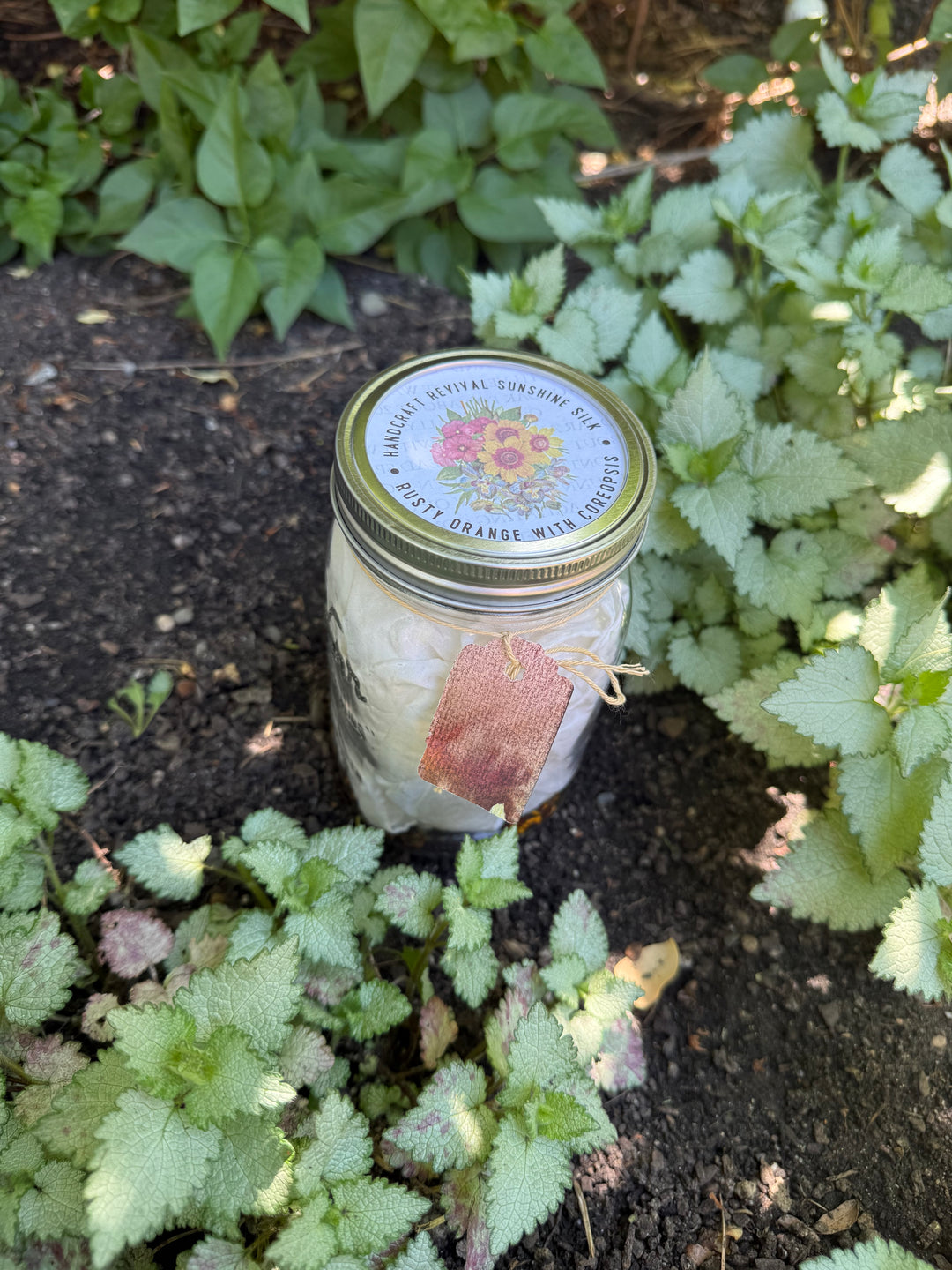A clear glass mason jar filled with white bath salts, featuring a gold metal lid with a floral label that reads &
