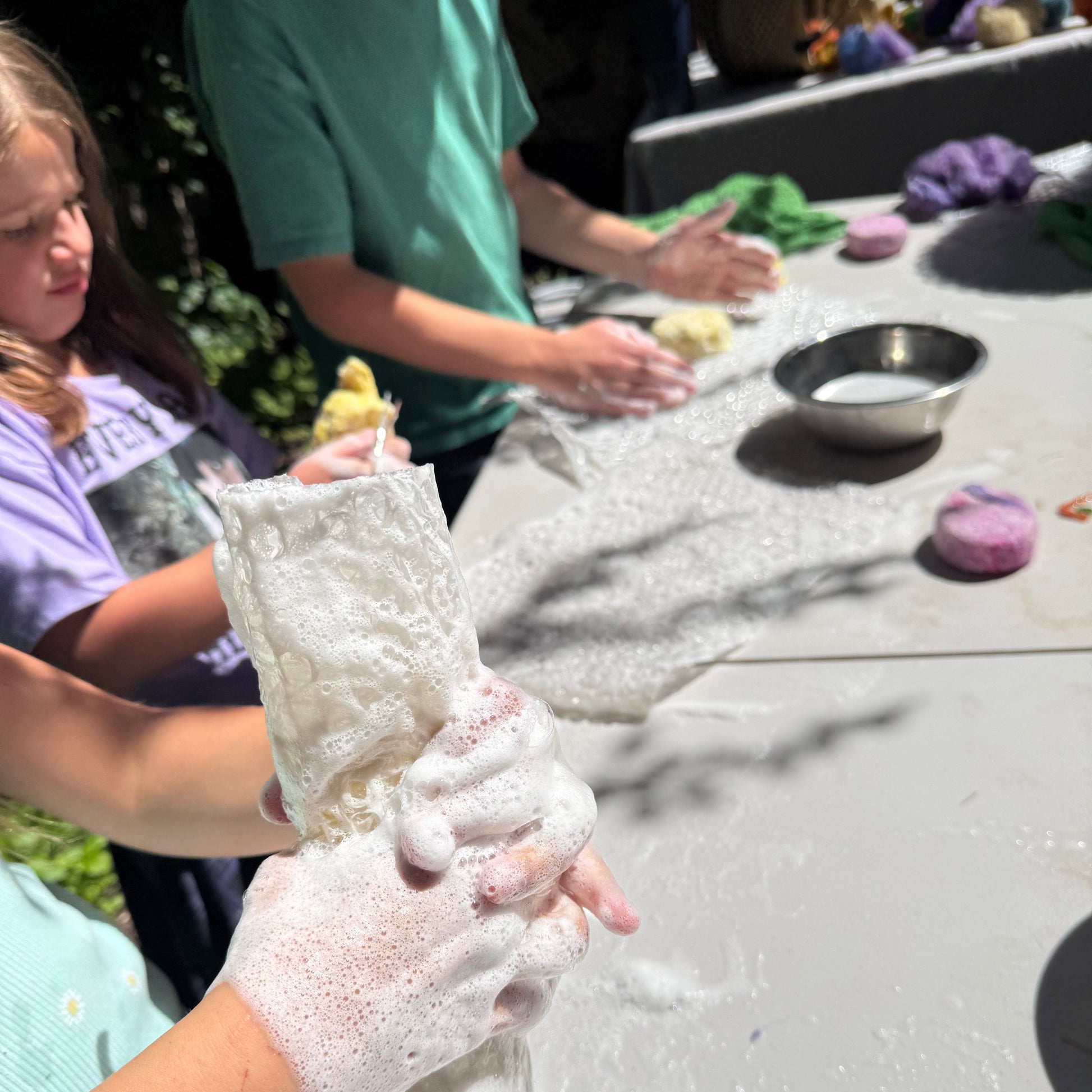 Person wearing white gloves with soap suds, climbing wall in the background